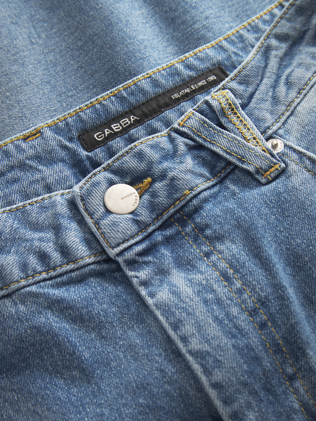 Close-up of GABMarc 5poc - Mid Blue Denim jeans by Gabba, showcasing a metal button, belt loops, visible stitching, and a black brand label on the waistband.