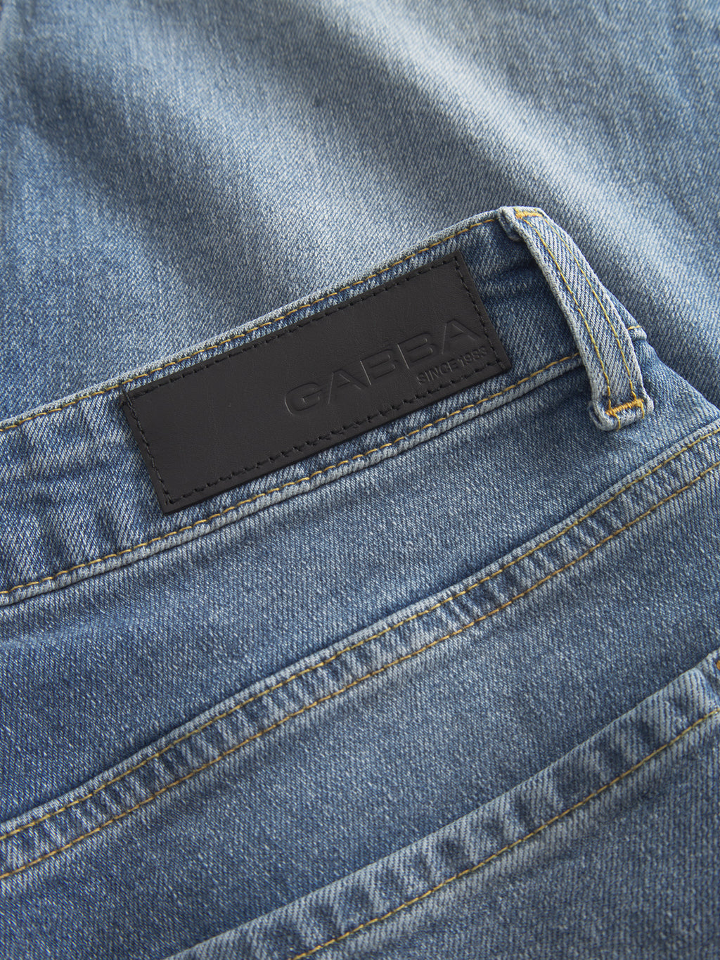 Close-up of the GABMarc 5poc mid blue denim regular fit jeans by Gabba, featuring the back pocket and a black leather patch embossed with the brand name.