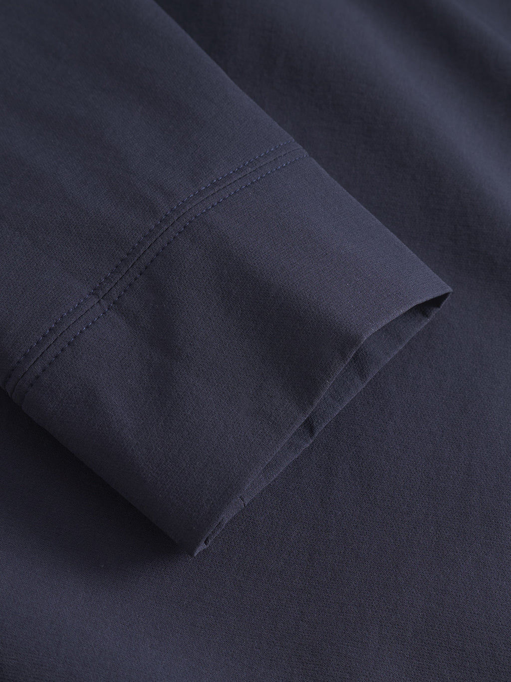 A close-up of the GABnik Tech - Navy shirt by Gabba highlights its durable tech fabric, clean seam, and smooth texture—ideal for an on-the-go lifestyle.