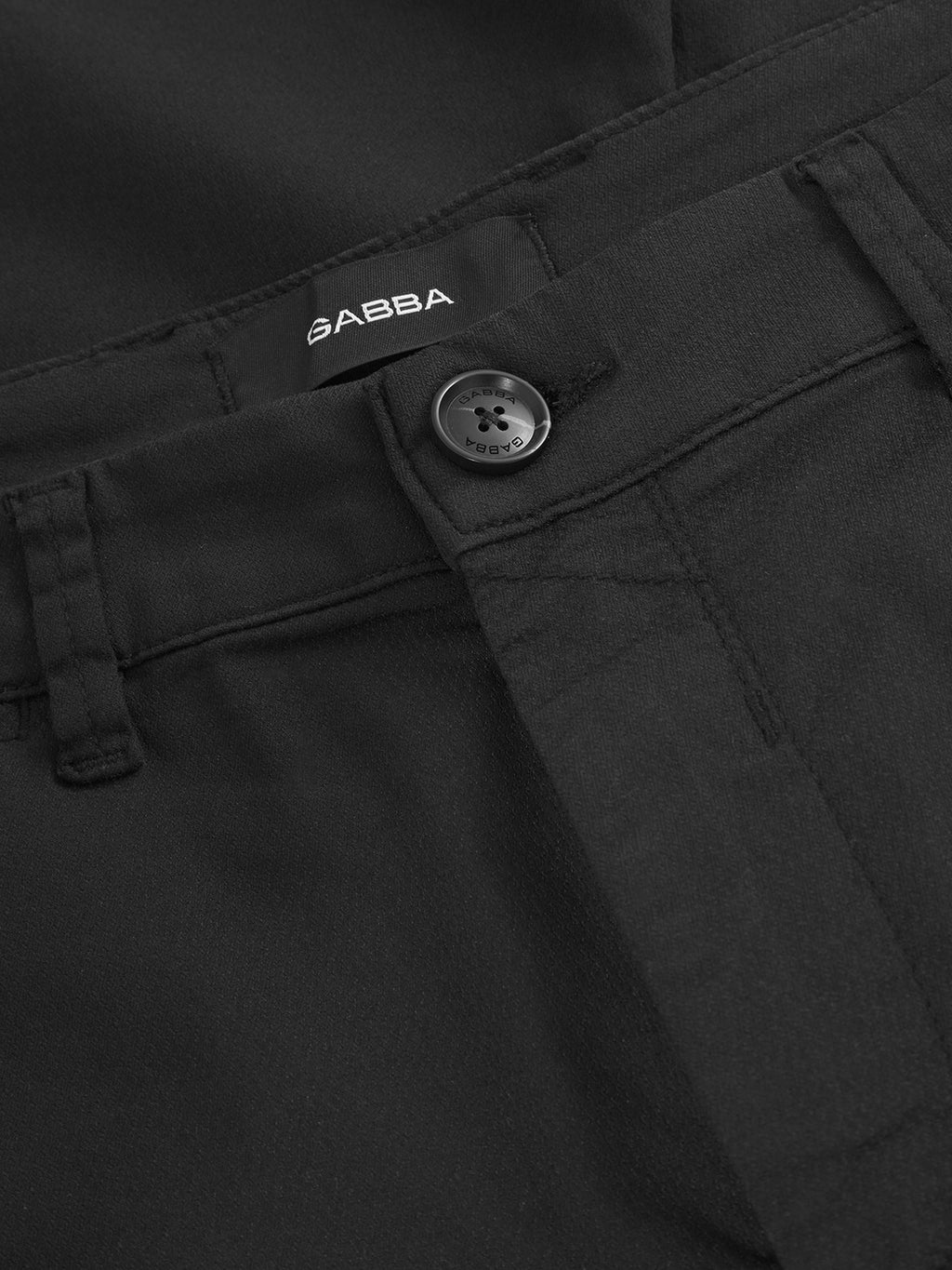 Close-up of the waistband and button on Gabba's Paul K3280 Cargo Dale - Black slim fit pants, showing belt loops, branded buttons, a button closure, SABBA label, and a glimpse of stylish cargo pockets.