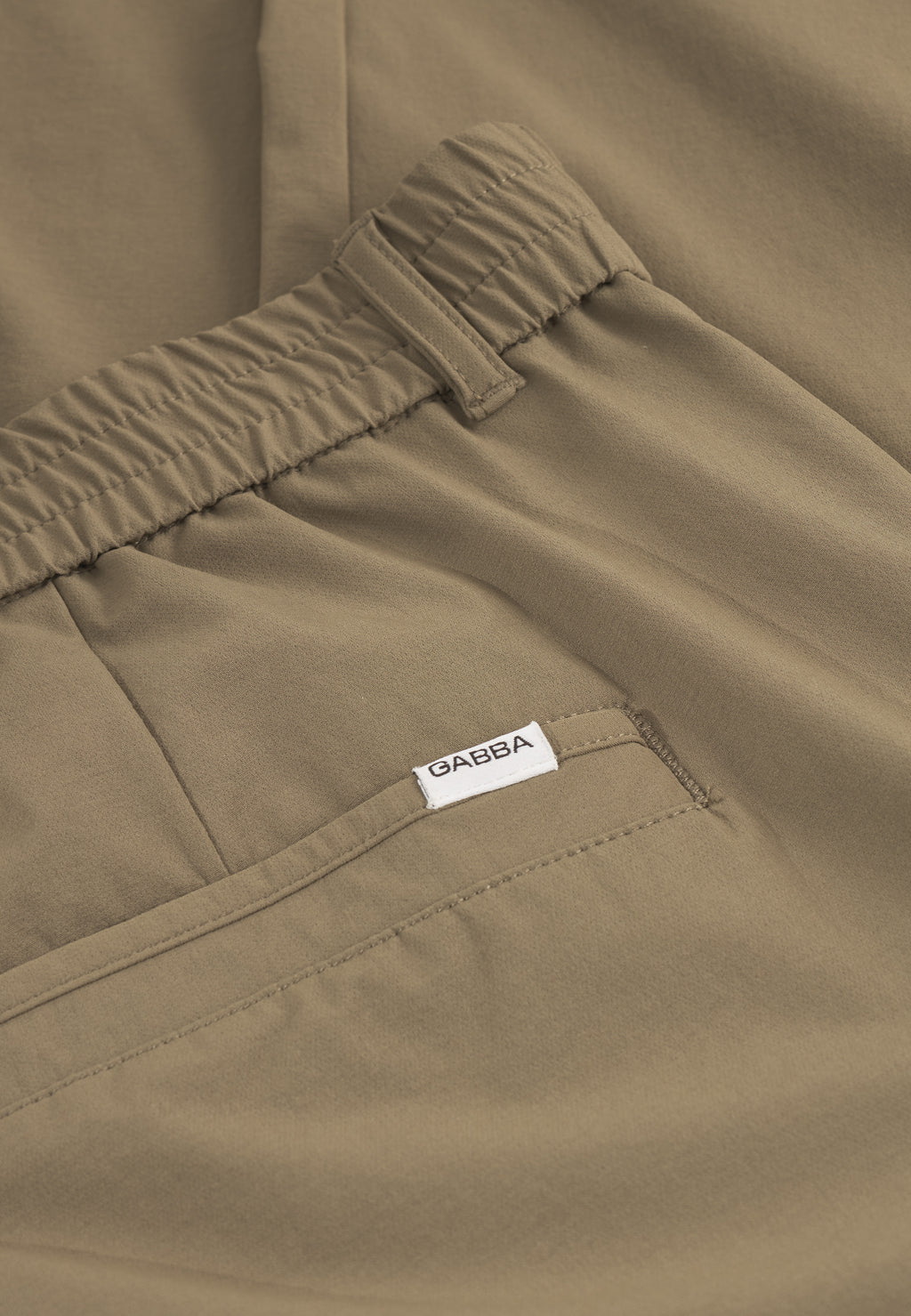Close-up of Gabba GABmonza Tech - Army pants in light brown, showcasing a relaxed straight fit, elastic waistband, visible stitching, and a back pocket with a small white Gabba label.