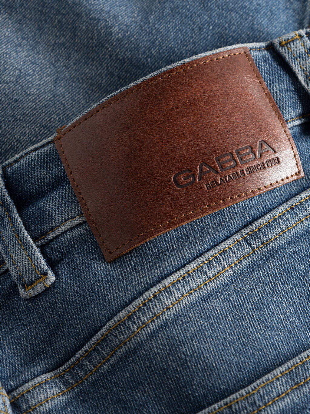 Close-up of GABBA Alex K3948 Jeans in denim wash, featuring a brown leather waistband patch embossed with 
