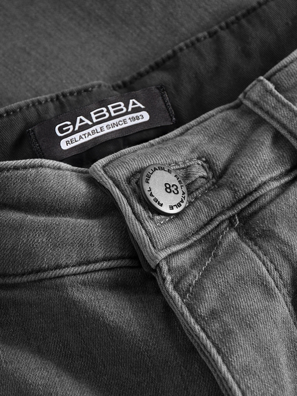 Close-up of GABBA's GABrey K3454 - Denim wash jeans, featuring a metal button engraved with 83 and Relatable, plus a GABBA RELATABLE SINCE 1983 label sewn on the waistband for an effortless laid-back vibe.