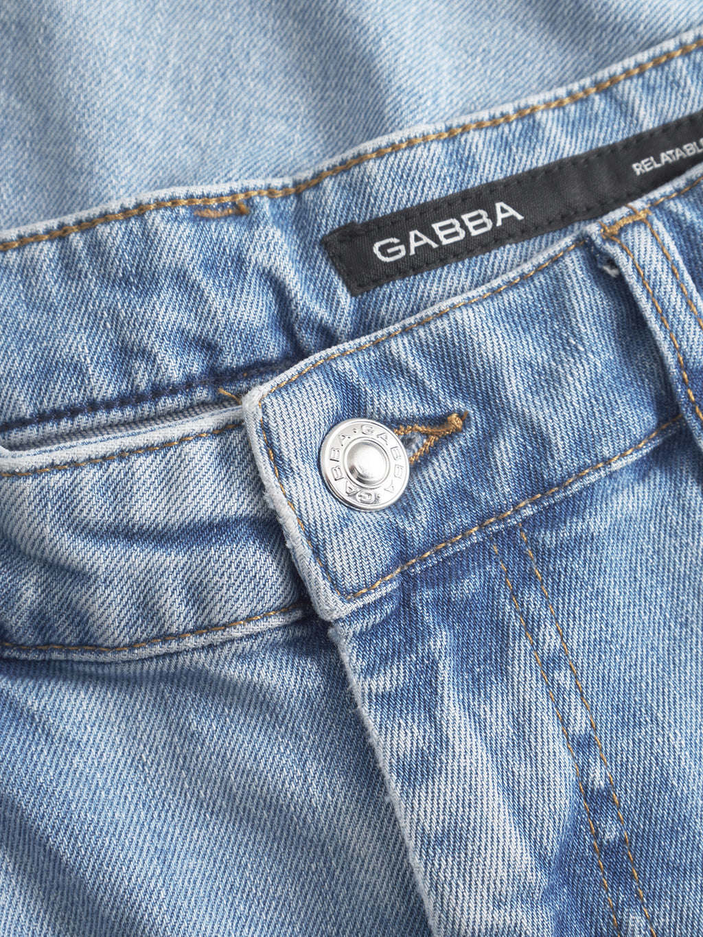 Close-up of GABmarc F1012 - Lt. Blue Denim jeans by Gabba, highlighting the classic fit waistband, silver button, belt loop, and black label with the Gabba brand name.
