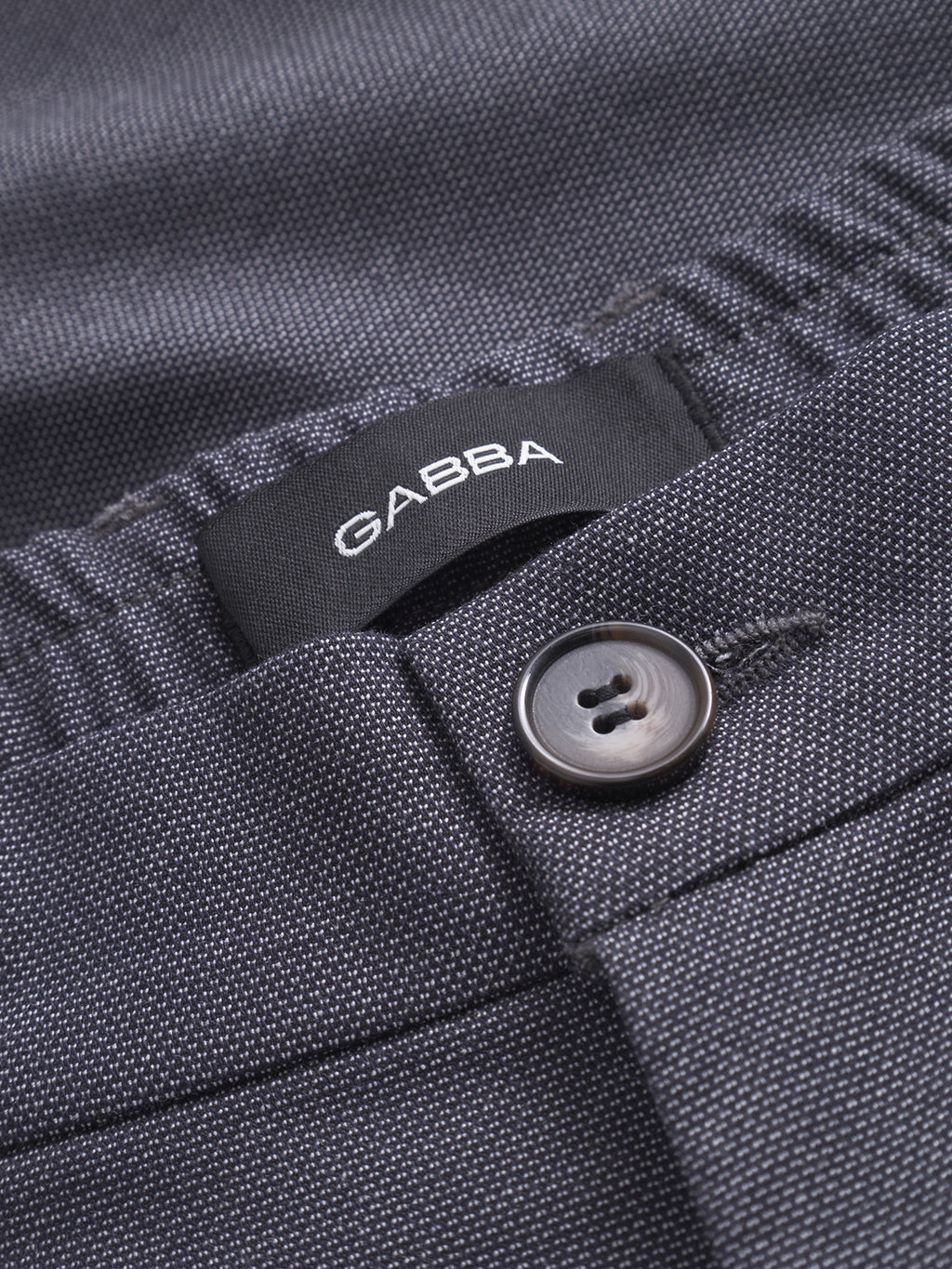 Close-up of navy textured Gabba Napoli 19 Carre pants featuring a button, visible black label, fine dotted pattern, classic style, and an elastic waistband for comfort.