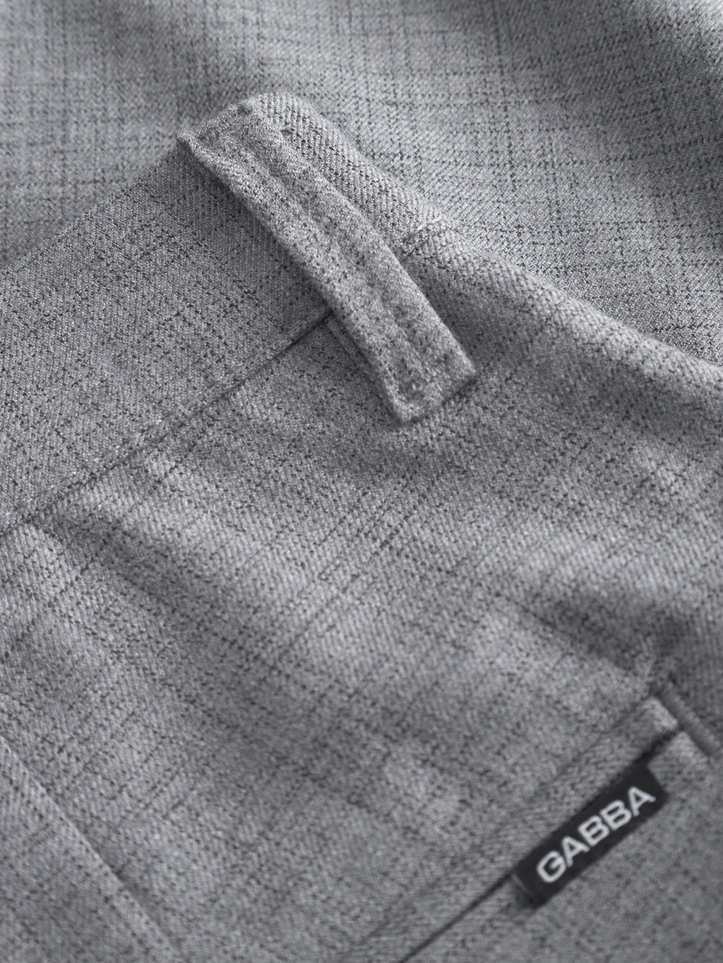 Close-up of Pisa Cross Lt Grey pants by GABBA, with gray stretch cotton-blend fabric, partial pocket, belt loop, and a black GABBA tag—showcasing signature metro style.