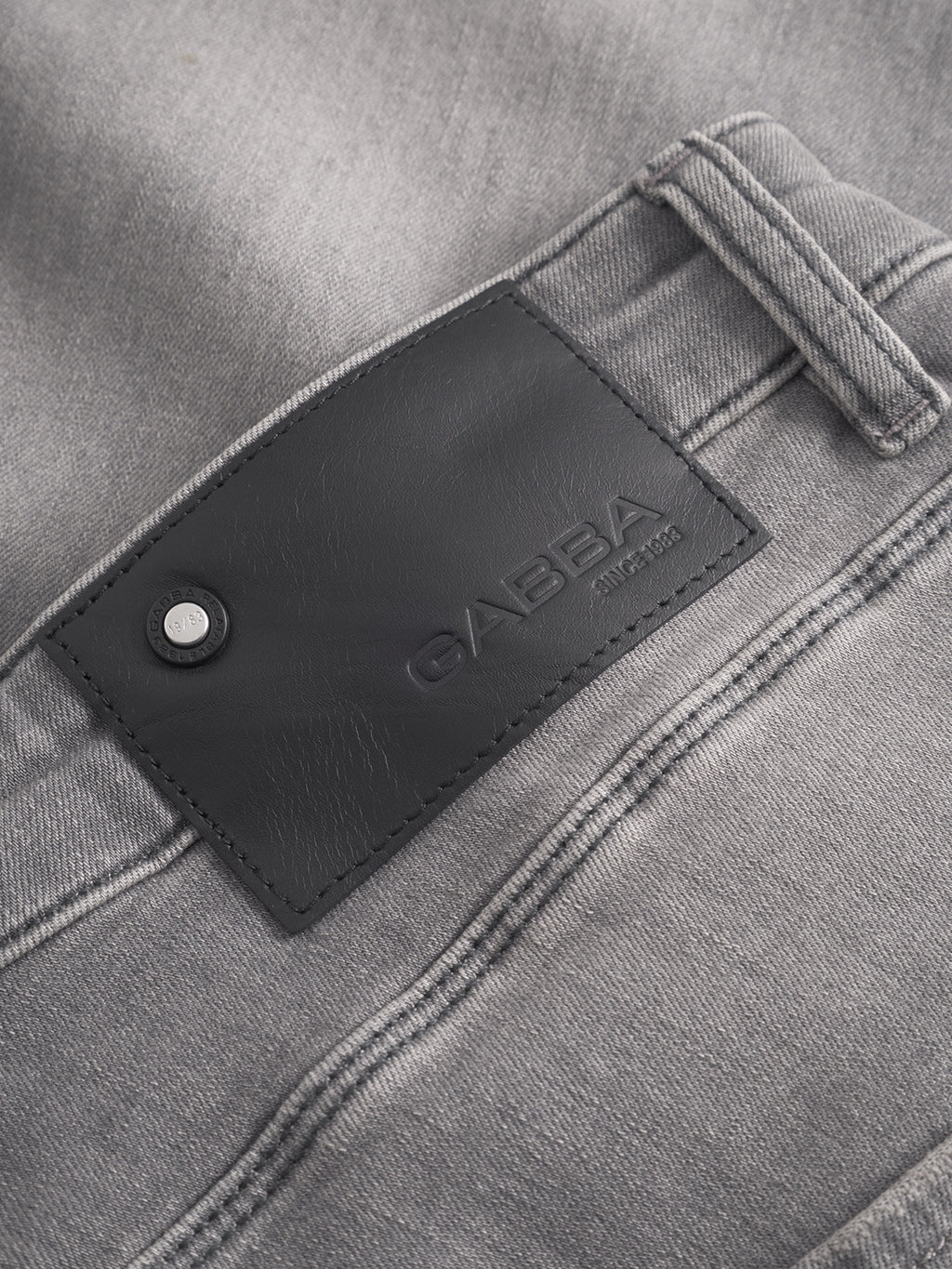 Close-up of light gray GABBA slim fit jeans, style GABrey K3454 - Denim wash, highlighting the back pocket with a black leather brand patch and stitched details for a laid-back look.