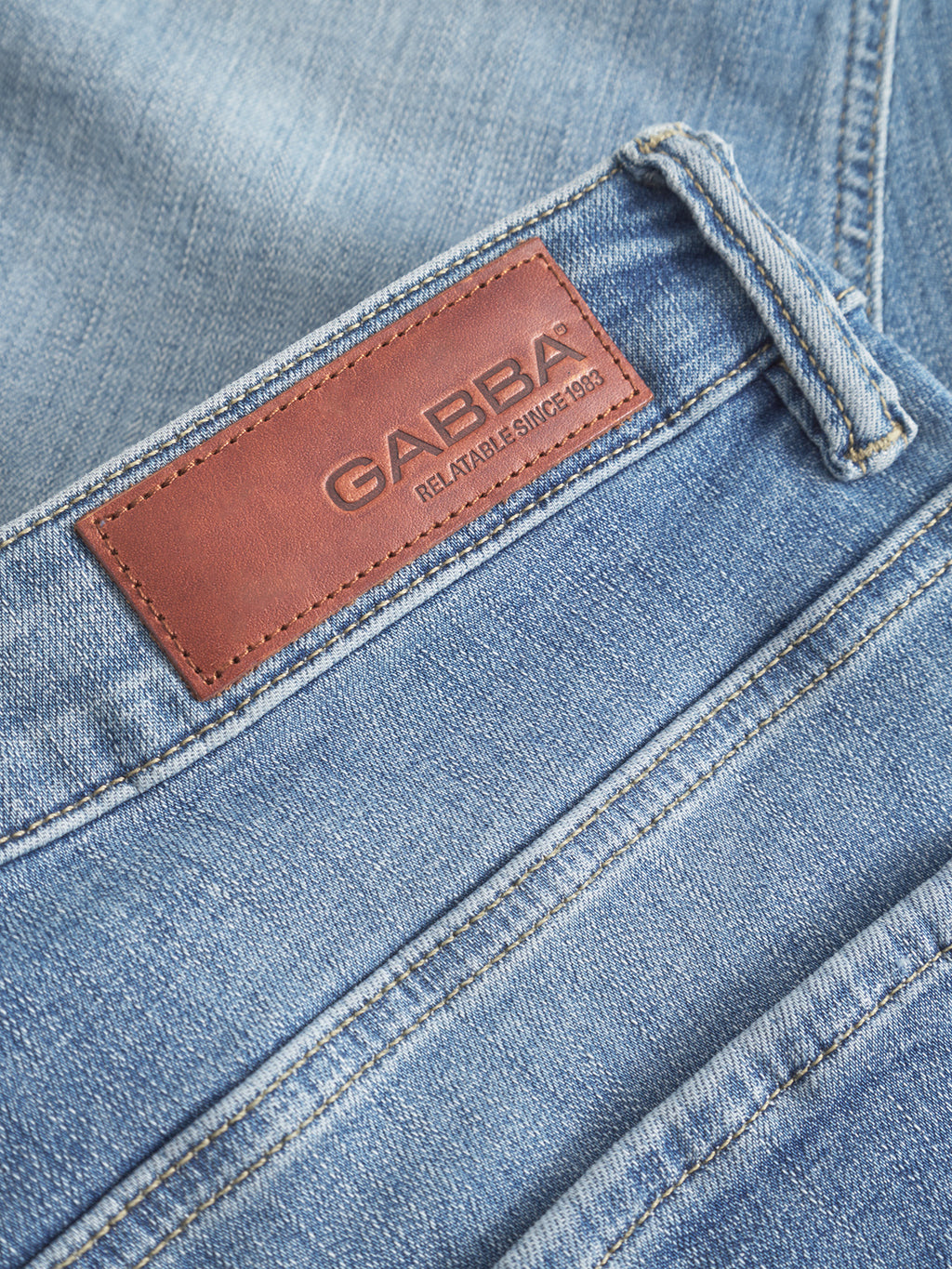 Close-up of GABBA GABjones K2615 Lt. denim wash slim jeans in light blue, featuring a brown leather waistband patch with the brand’s name and 