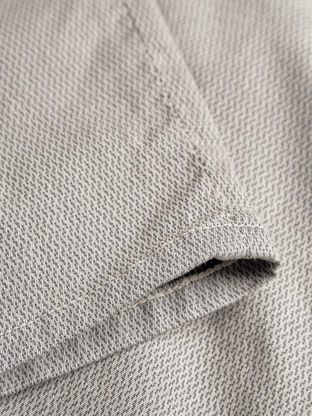 Close-up of the Gabba GABpaul K3280 Dale Chino in Birch shows light gray fabric with a small chevron pattern, visible edge stitching, neat folds, and French pockets—highlighting the chino’s smooth texture and classic slim style.
