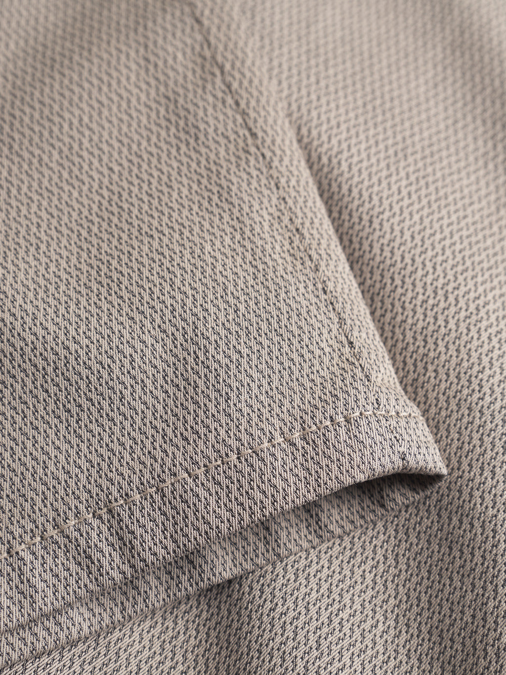 Close-up of two overlapping pieces of beige fabric from the GABBA GABpaul K3280 Dale Chino - Humus, featuring a subtle herringbone pattern—ideal for classic slim chinos with French pockets and neat stitching.