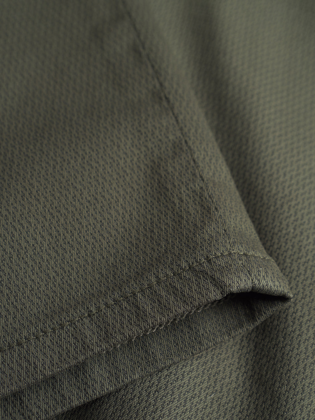 Close-up of GABBA GABpaul K3280 Dale Chino - Army fabric in olive green, featuring a subtle texture, visible edge stitching, and refined details inspired by slim chino pant French pockets.
