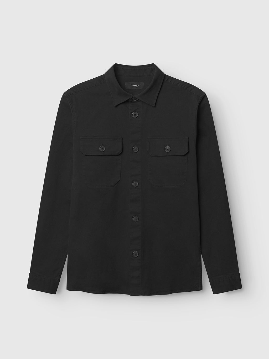 The GABBA GABtopper LS Shirt in black is laid flat against a plain light gray background, showcasing its classic shirt collar, long sleeves, and two chest pockets with button flaps.