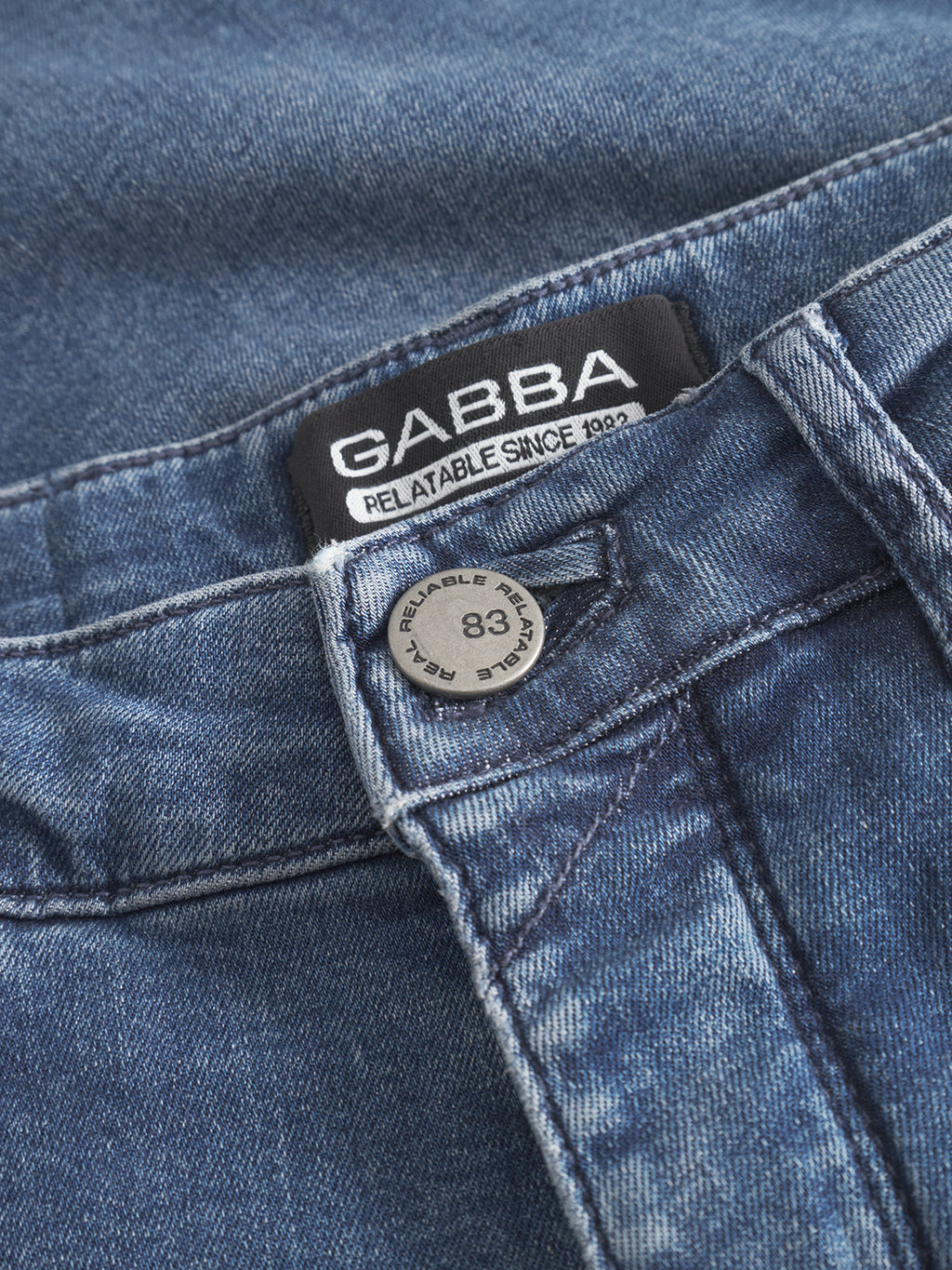Close-up of GABBA GABrey K3866 TENCEL™ Jeans in denim wash featuring a visible metal button stamped 83 and a GABBA RELATABLE SINCE 1983 waistband label, with classic stitching and texture for a laid-back style.