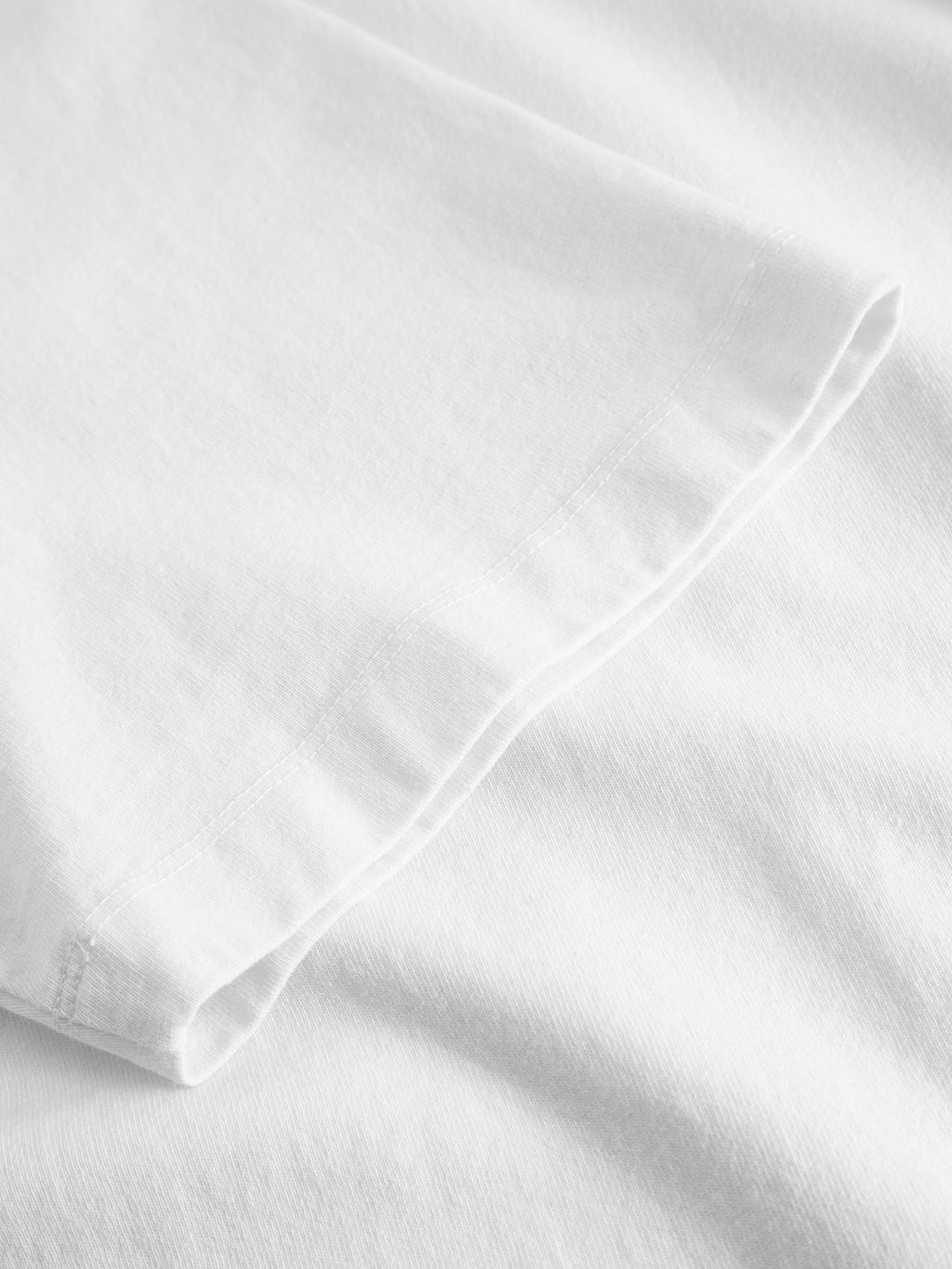 Close-up of the sleeve and body of the Gabba GABnigel Wix Boxy Hour SS - White, highlighting its heavyweight cotton texture and detailed stitching.