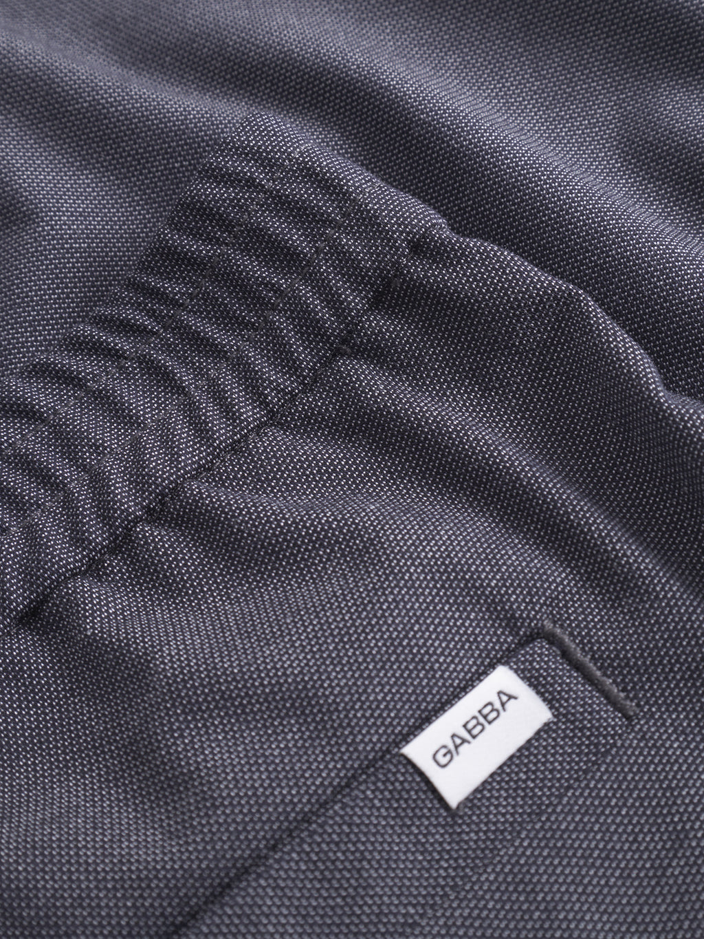 Close-up of navy Napoli 19 Carre classic pants by Gabba, featuring an elastic waistband and a white Gabba label sewn near the seam.
