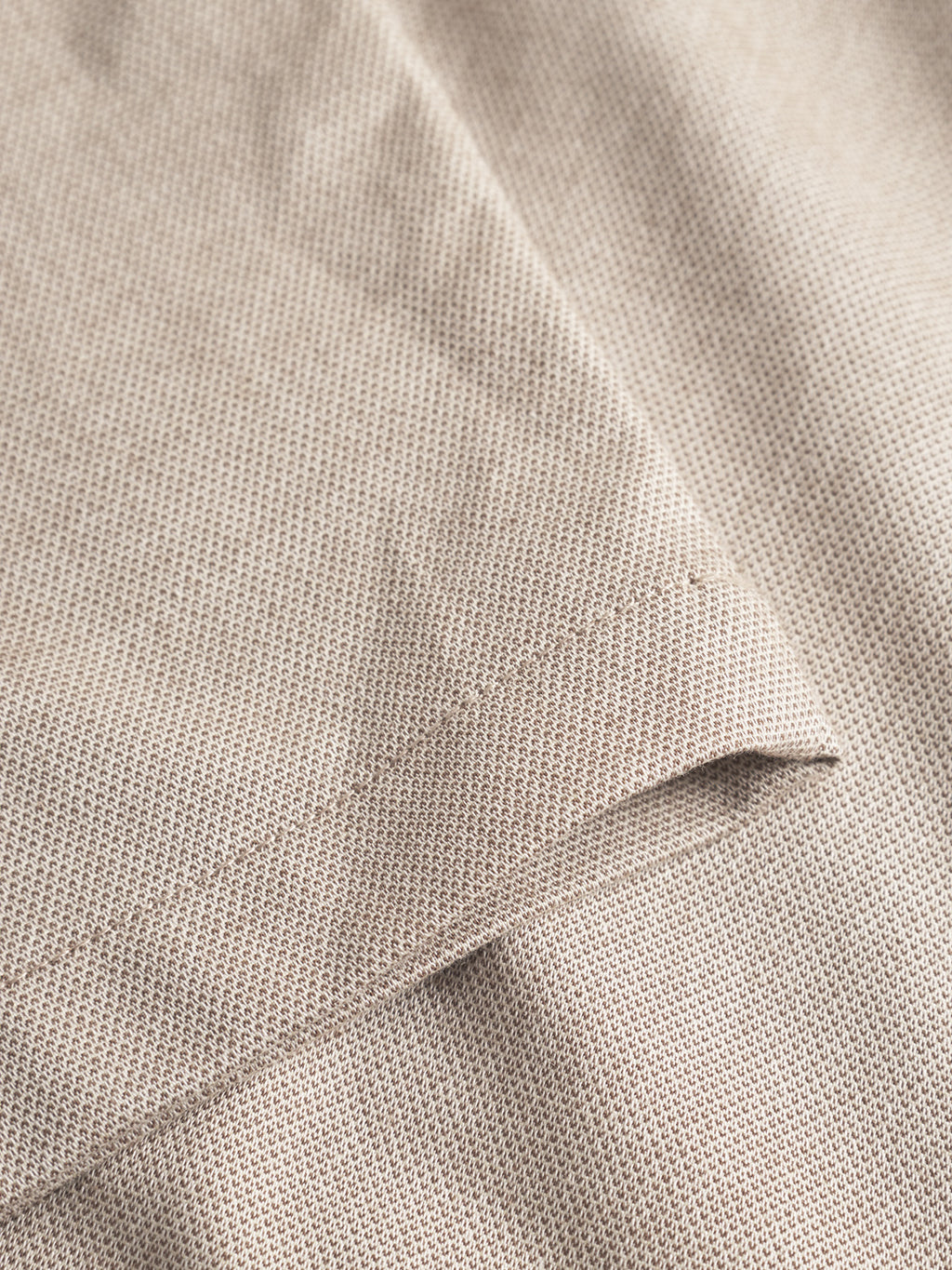A close-up of the beige textured fabric of Gabba's Napoli 19 Carre - Sand pants showcases the fine weave, soft material, visible seam, and a neatly folded corner.