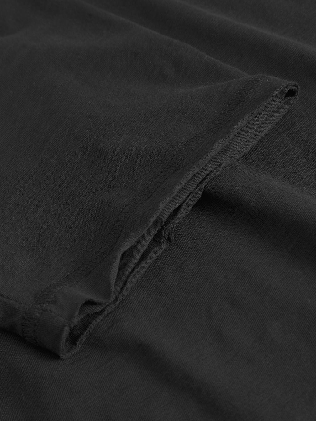 Close-up of the textured black fabric and stitching on the GABkostant New SS - Meteorite by Gabba, highlighting the detailed hem and premium 100% cotton material.