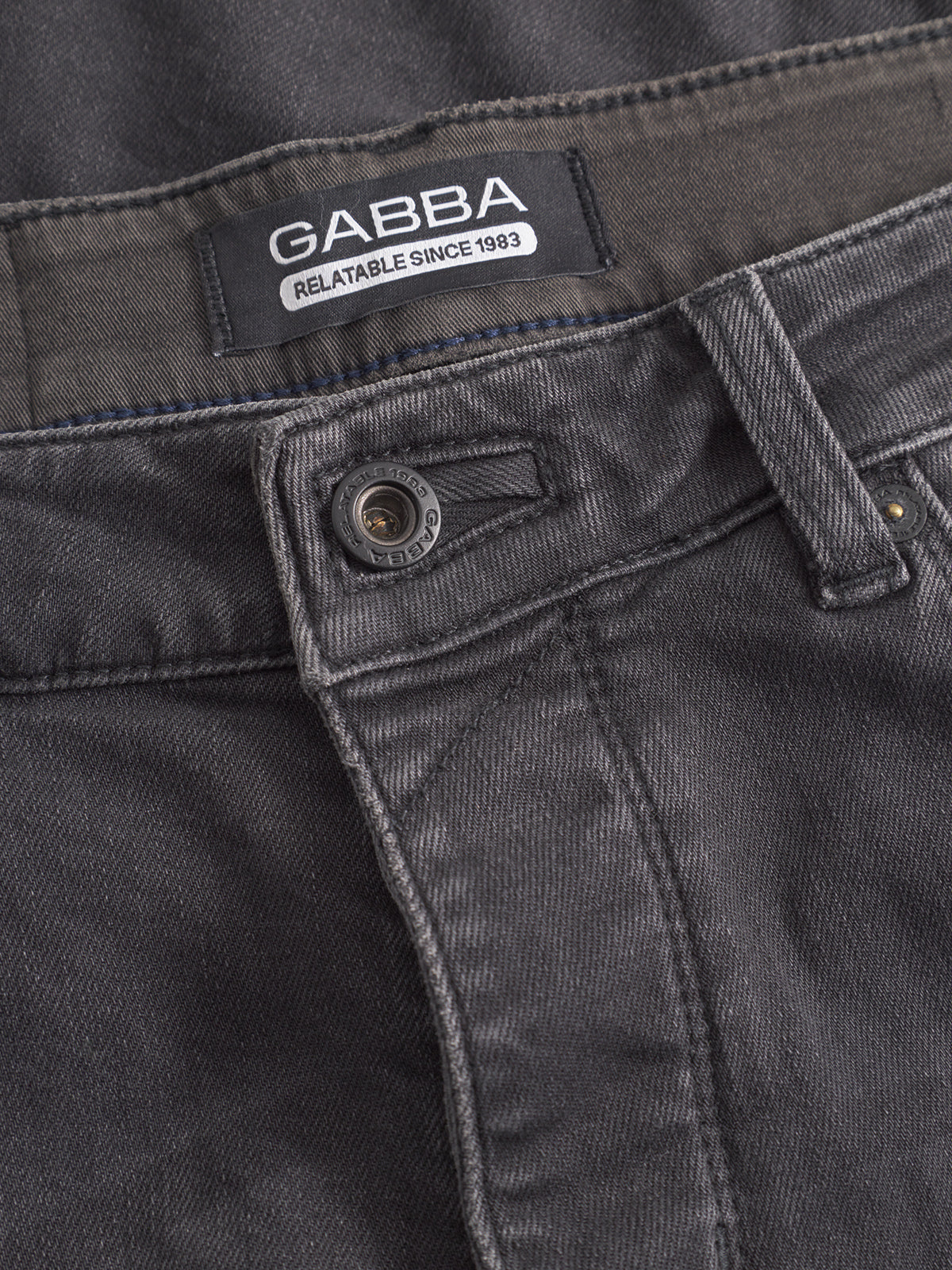 Close-up of the waistband and front button of GABBA GABrey Thor Jeans in denim wash, featuring an inner label and a textured, slightly faded fabric ideal for laid-back style.
