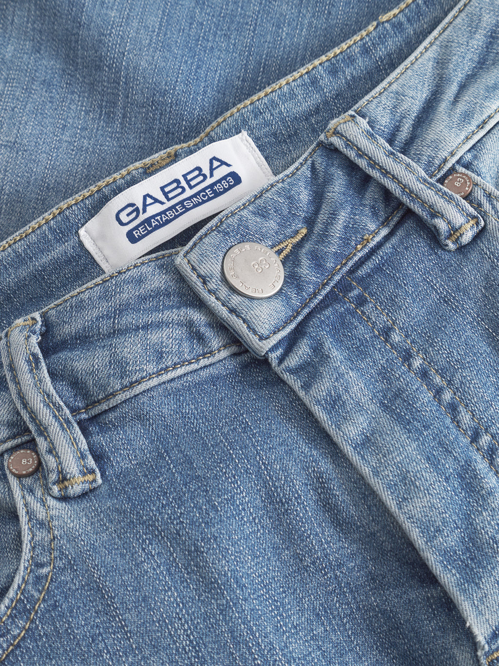 Close-up of GABBA GABjones K2615 Lt. - Denim wash slim jeans, featuring a blue waistband, button, and a white label with blue text 