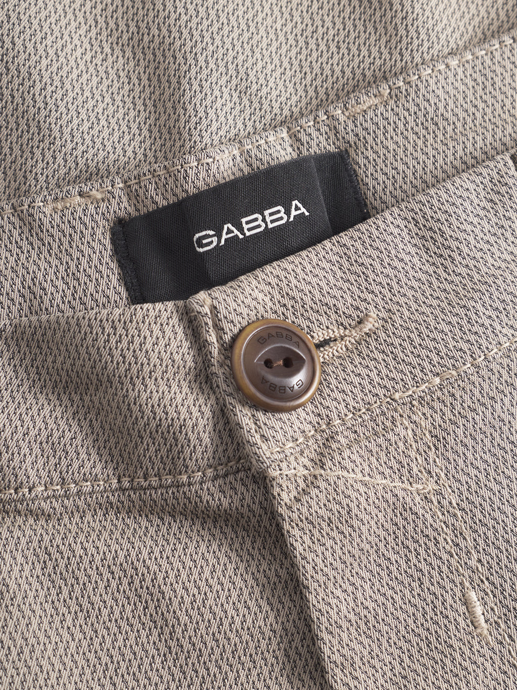 Close-up of the GABBA GABpaul K3280 Dale Chino in Humus: beige slim-fit pants with French pockets, a brown button, and a black GABBA label above the waistband.