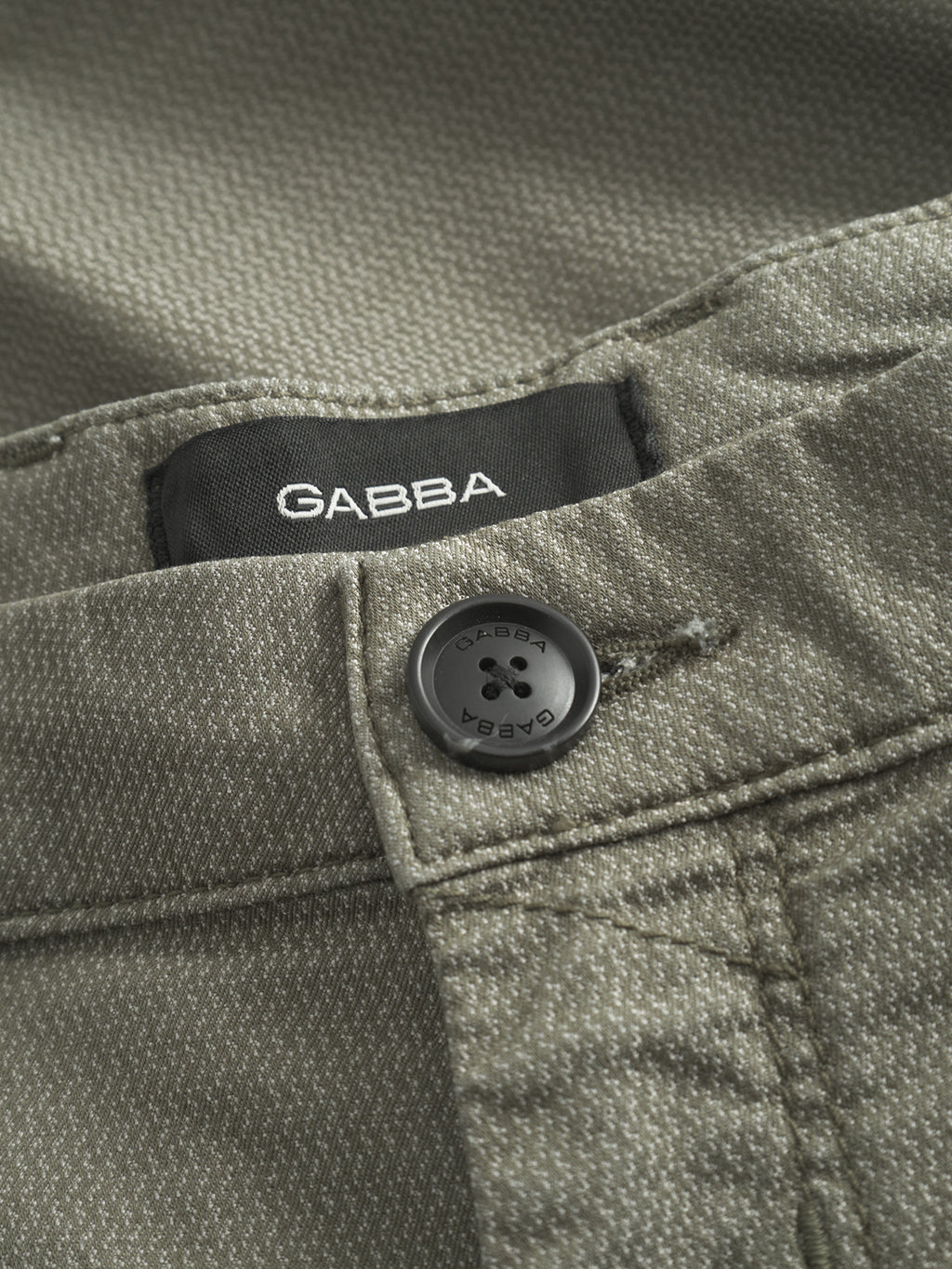 Close-up of Gabba GABpaul K3280 Dale Chino in olive green, featuring a textured slim fit, French pockets, a black button engraved with Gabba, and a black fabric label with white Gabba lettering.