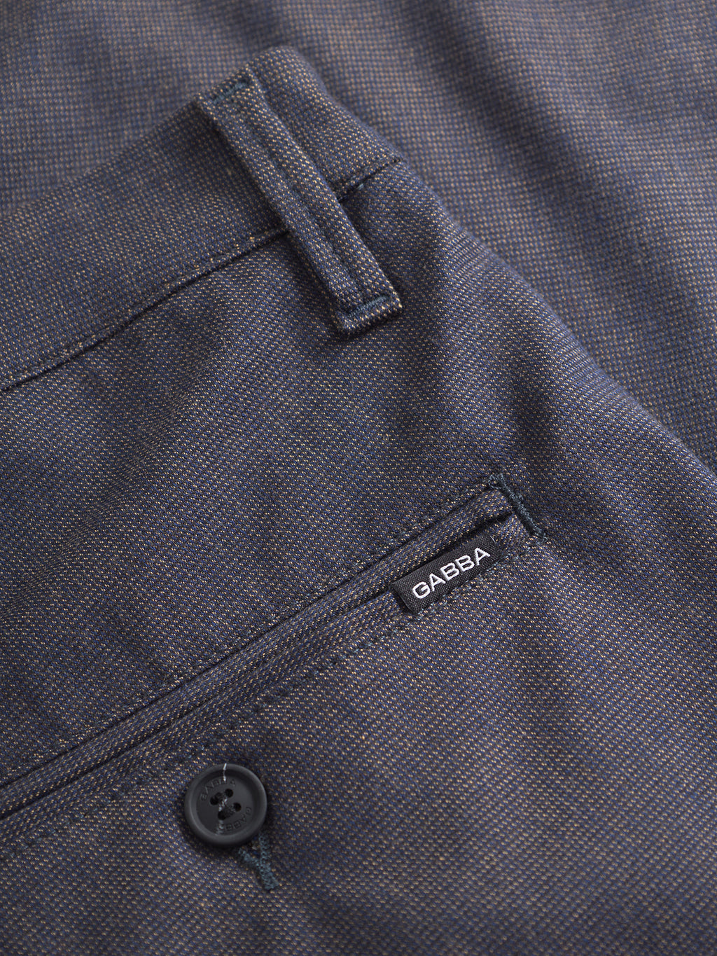 Close-up of Gabba's Paul Domo slim chino pants in dark navy melange, featuring textured fabric, French pockets, visible back pocket, black branded button, belt loop, and a small black GABBA label.