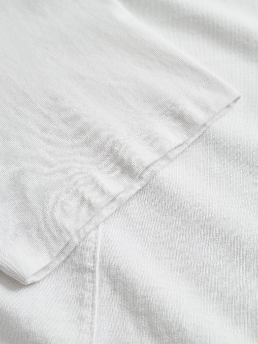 Close-up of the sleeve and body of the Gabba GABnigel Wix Boxy Hour SS in white, showcasing the heavyweight cotton fabric's texture and detailed seams.