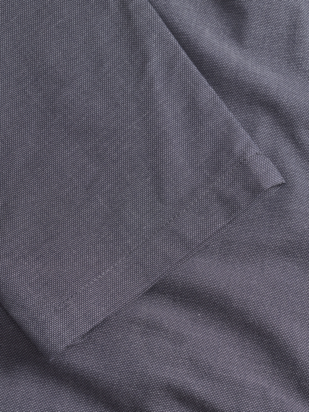Close-up of navy textured fabric from Gabba’s Napoli 19 Carre pants, showing a subtle grid pattern. The slightly wrinkled folds highlight the classic stitching and clean seam edge that define these comfortable pants.