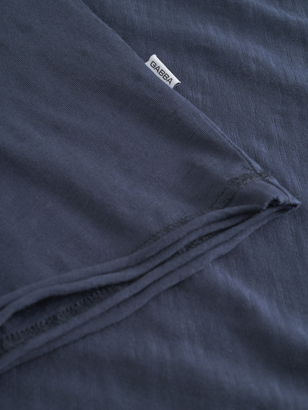 Close-up of the Gabba GABkostant New SS t-shirt in navy, made from 100% cotton with textured fabric and visible stitching, featuring a small white Gabba label sewn into the seam.