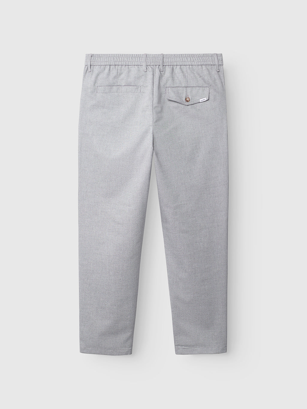 Back view of Gabba Monza Button Carre pants in light grey. These relaxed straight pants feature an elastic waist, two back pockets—a buttoned flap on the left and a slit on the right—and have a smooth, subtly textured fabric.