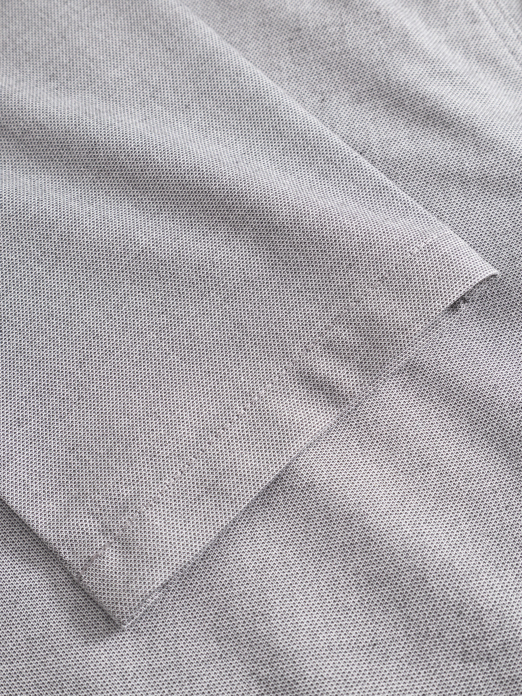 Close-up of the Gabba Monza Button Carre in light grey—a short-sleeve cotton shirt with fine dots and a neatly folded sleeve, perfect for versatile everyday style or pairing with relaxed straight pants.