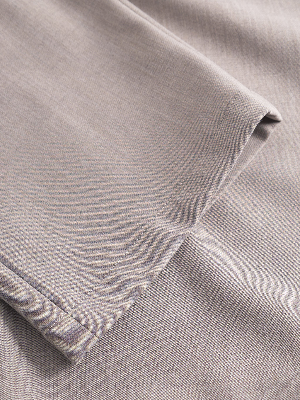 A close-up of a light gray fabric from the Gabba GABnapoli 19 Phin GRS - Sand, showing a neatly stitched hem and smooth texture, likely part of this regular straight fit wool blend chino or pant leg.