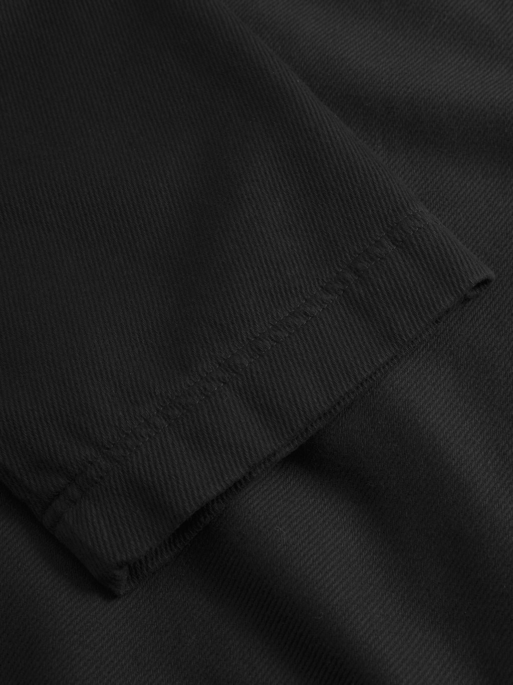 Close-up of the GABJoe‑Pas Vill - Black sleeve by Gabba, showcasing its visible stitching detail. The black fabric is laid flat against a matching background for an understated look—perfectly complementing relaxed fit trousers for effortlessly refined style.