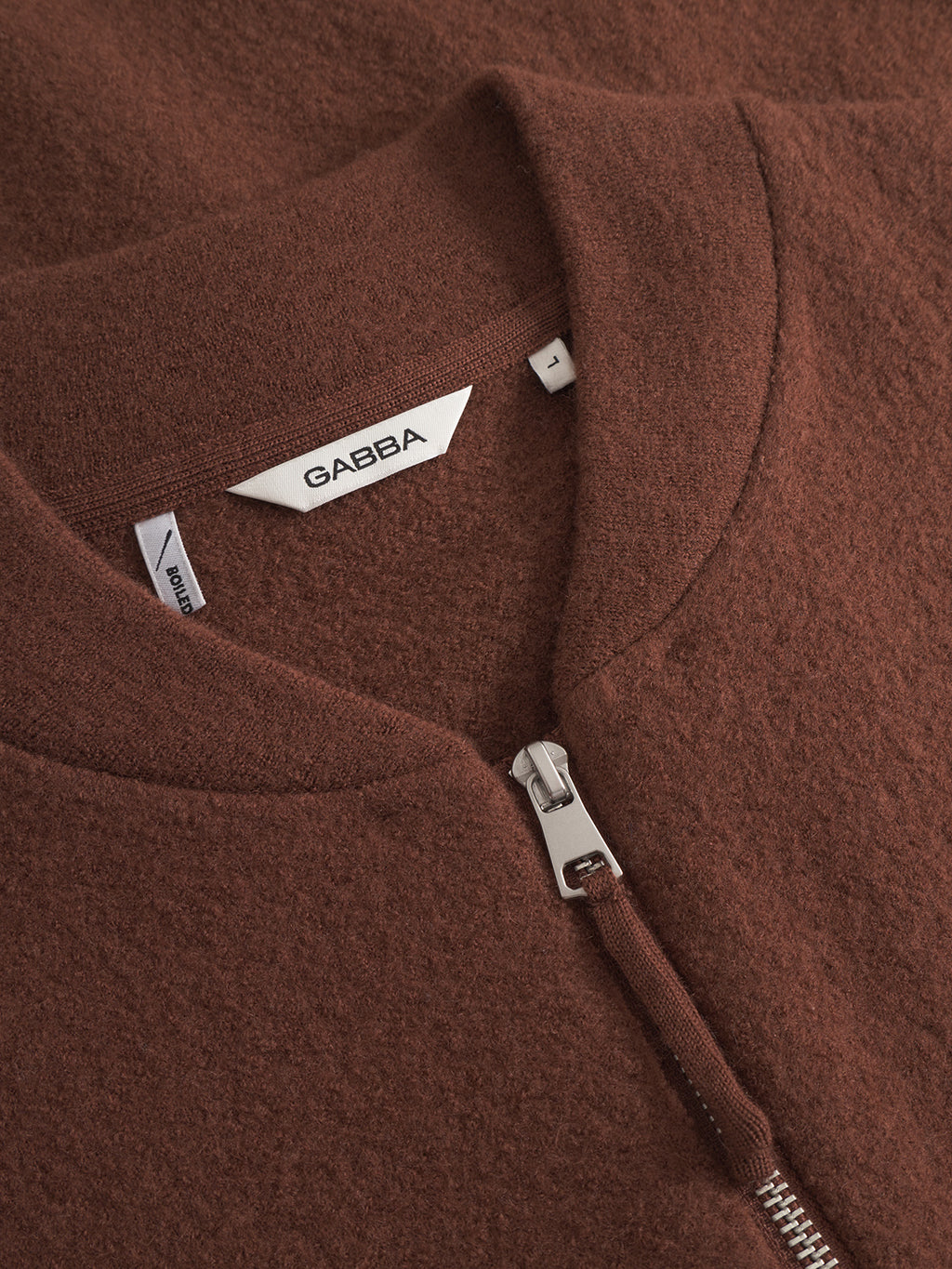 Close-up of the Cardiff Led - Brownish zip-up jacket by Gabba, made from brown boiled wool with a silver zipper, modern tailoring, a white Gabba tag, and an L size label near the collar.