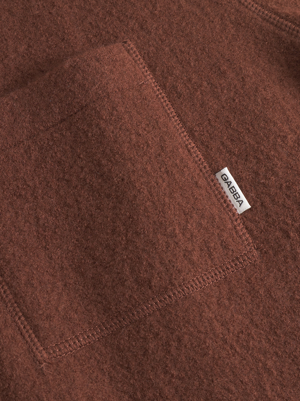 Close-up of Cardiff Led - Brownish by Gabba, featuring textured brown boiled wool with a stitched pocket and a small white OAKBA label on the seam, evoking classic wool bomber jacket style.