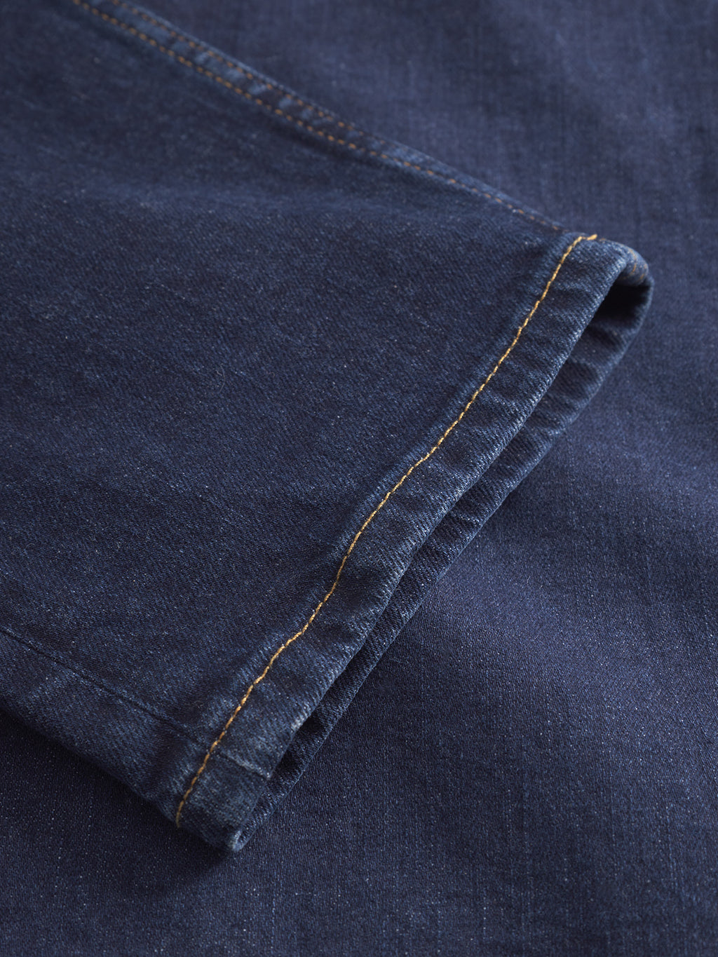 Close-up of a folded hem on Gabba GABmarc Jingo dark blue denim jeans, highlighting the yellow stitching and the textured comfort stretch fabric.