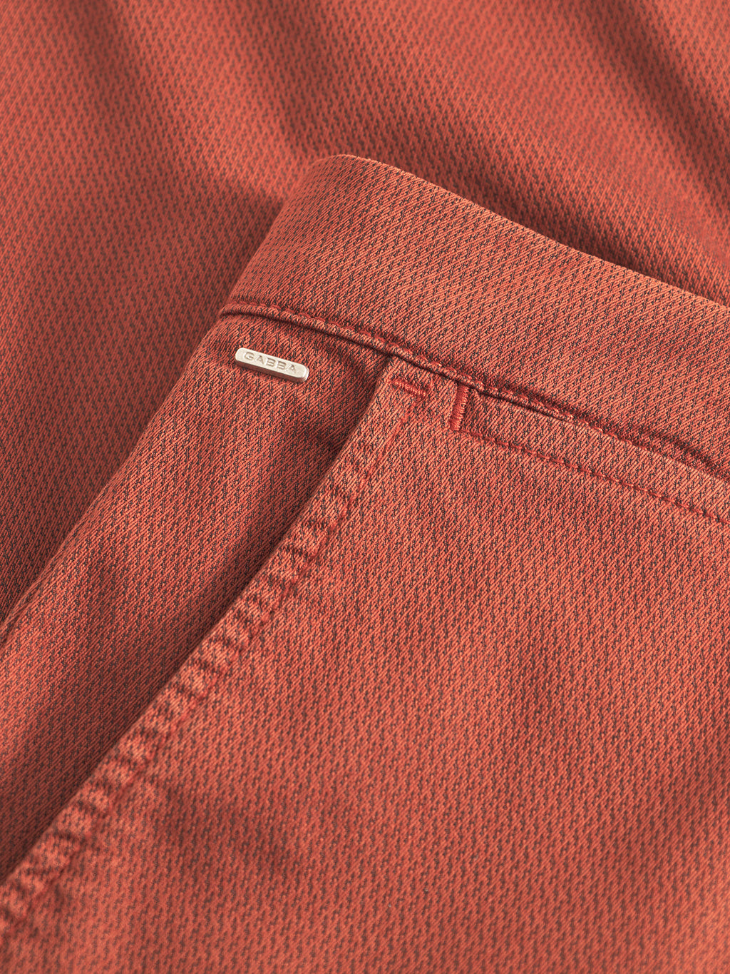 Close-up of Gabba’s GABpaul K3280 Dale Chino in Brown Rust, featuring textured fabric with a subtle pattern, French pockets, a slim leg opening, and a small metallic tag near the seam.