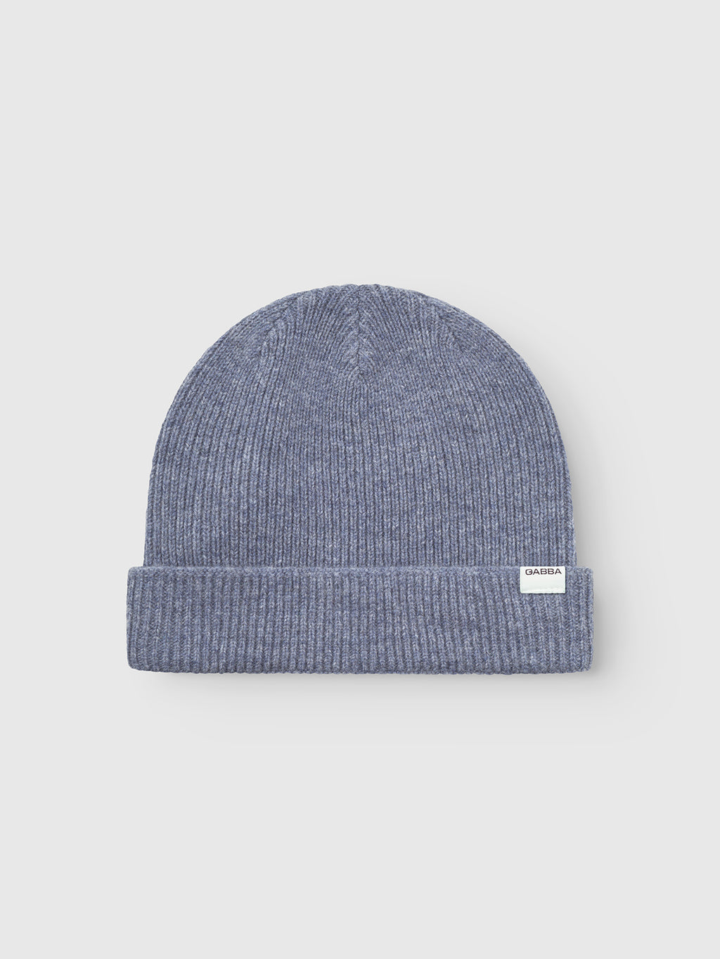The Gabba Biella Aico - Vintage Indigo is a light grey-blue ribbed knit beanie with a folded brim and small white rectangular label on the cuff, shown against a plain light background.