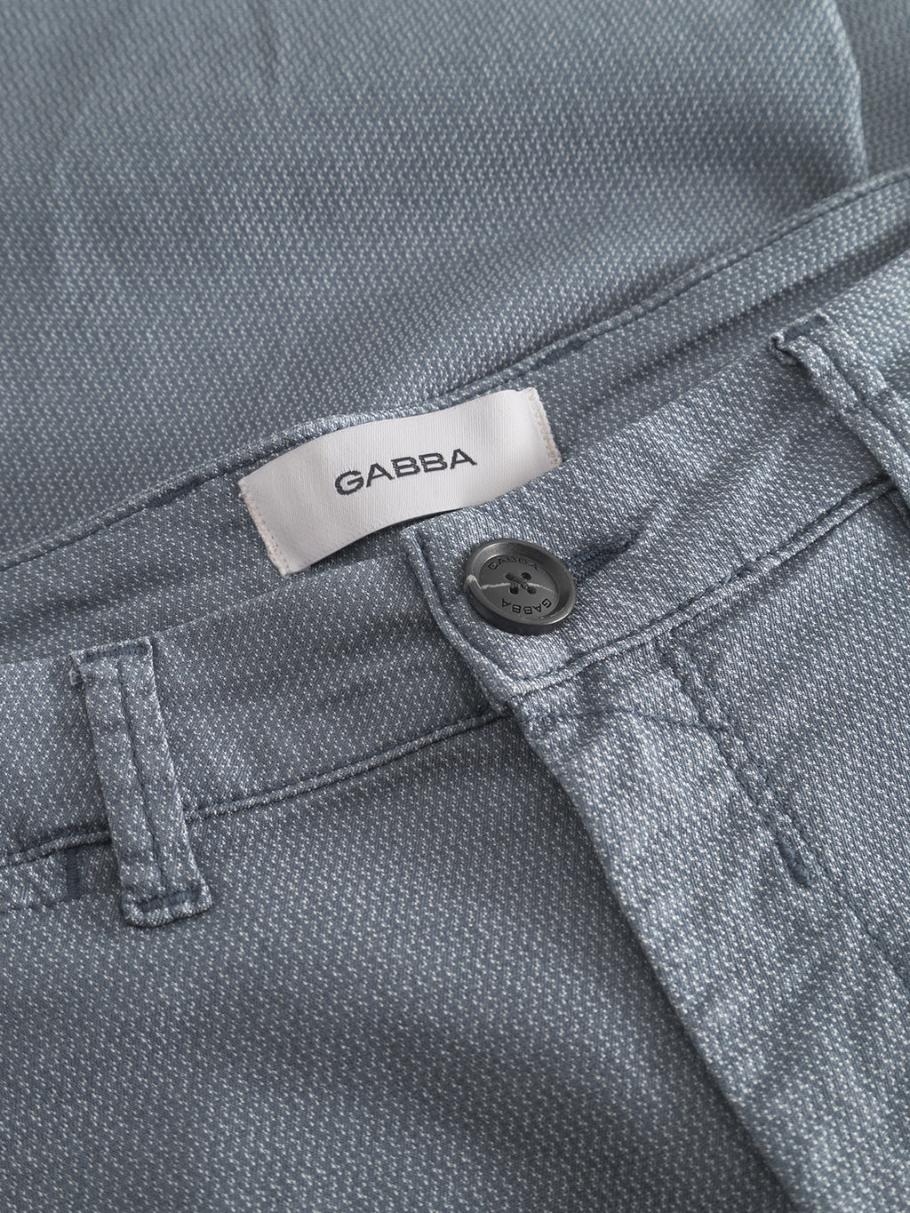 Close-up of the Gabba GABpaul K3280 Dale Chino in blue, showing French pockets, waistband with belt loop, black button, white Gabba label, and a subtle dotted fabric pattern.