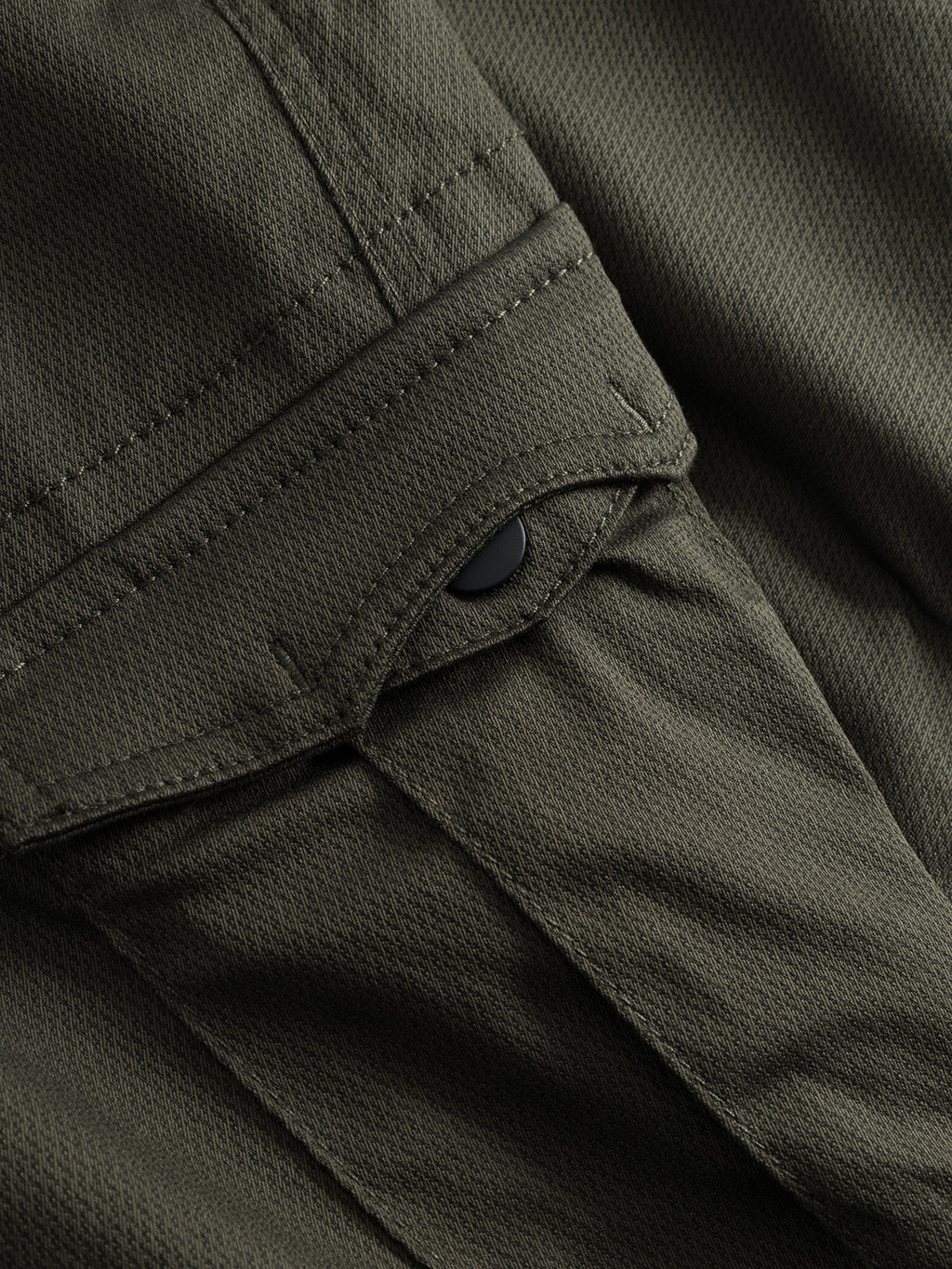 Close-up of GABBA Pisa Cargo K3280 Dale Pants in Army, highlighting a flap pocket with black snap button, visible stitching details, and the textured super stretch fabric.