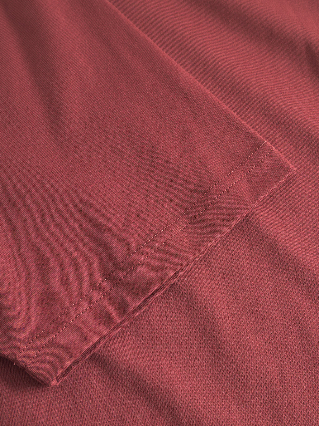 Close-up of the Gabba GABdune Logo GOTS SS T-Shirt in Red Russet, showing the detailed stitching along the sleeve hem against matching organic cotton fabric.