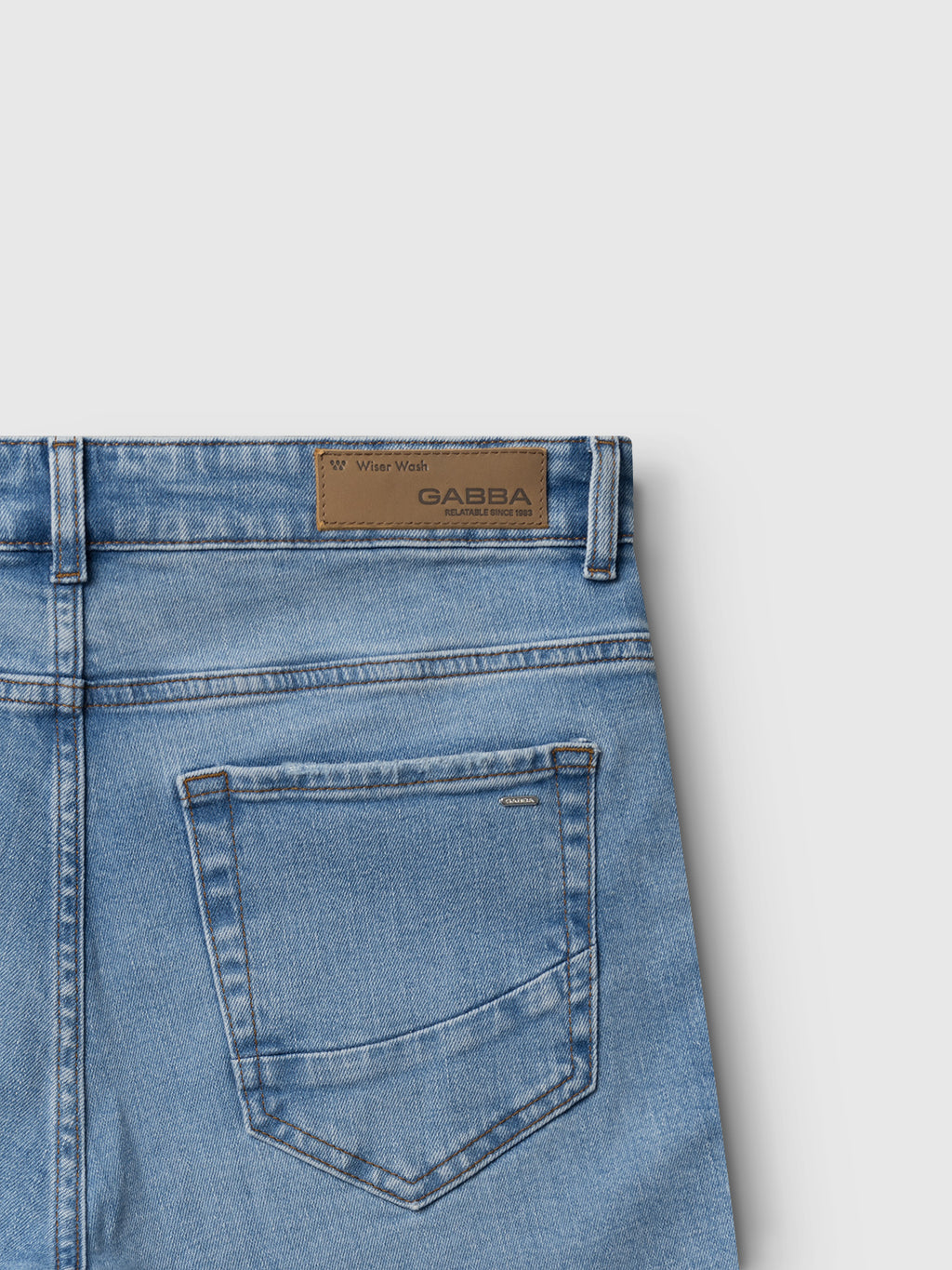Close-up of the back of Gabba GABmarc F1012 - Lt. Blue Denim jeans, featuring a single rear pocket, brown leather Gabba patch on the waistband, visible stitching, and belt loops.