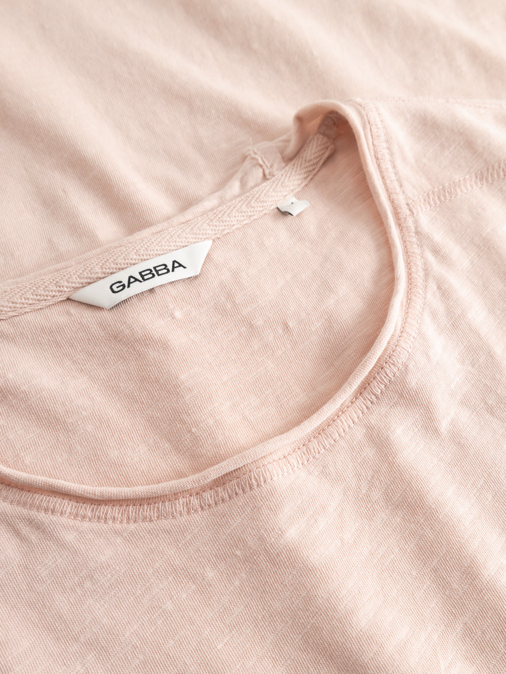 A close-up of the Gabba GABkostant New SS t-shirt in Misty Rose shows its soft, subtly textured 100% cotton slub fabric and round neckline. A white label inside the collar features the Gabba brand name.