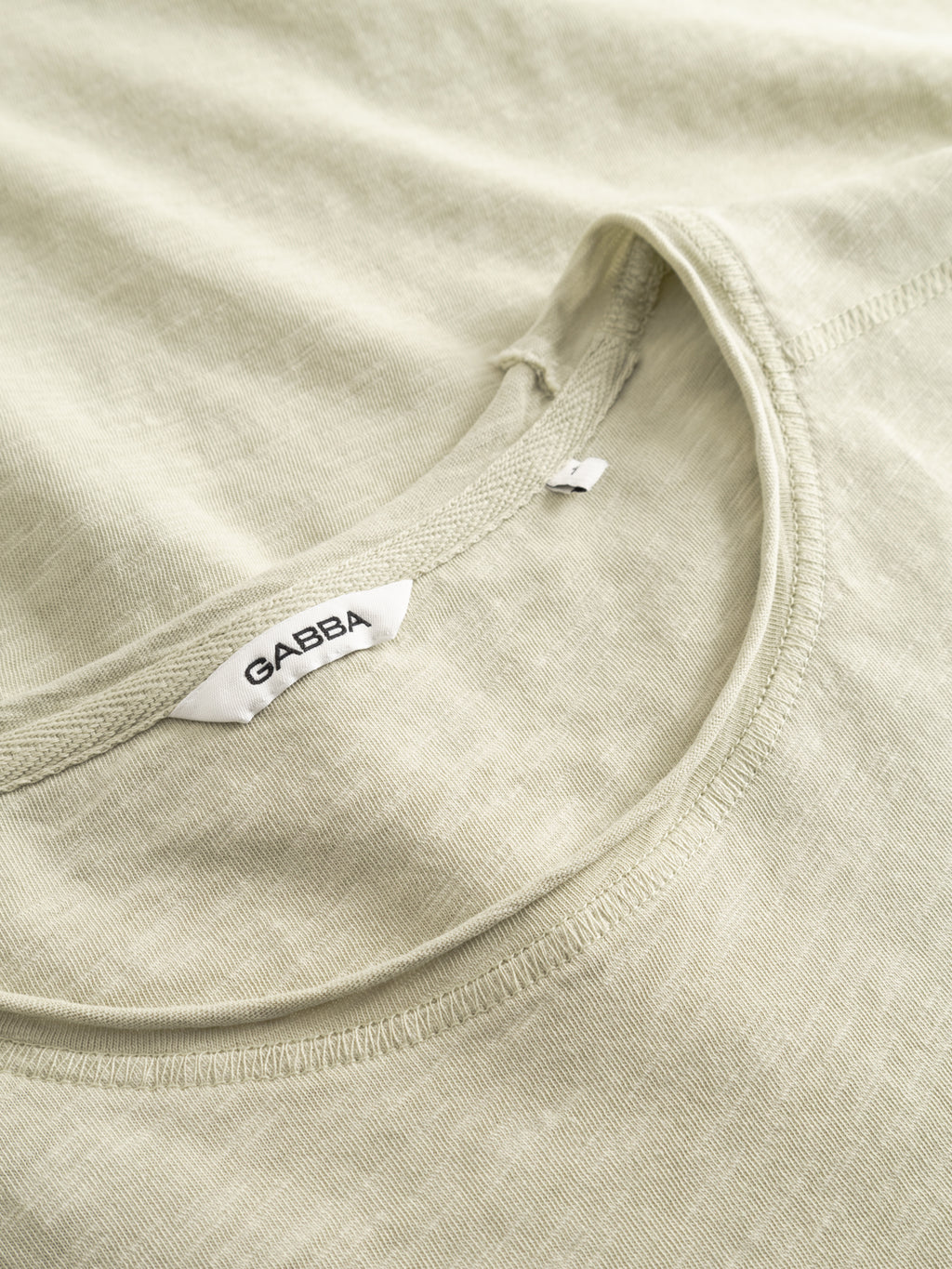 A close-up of the Gabba GABkostant New SS t-shirt in Alfa Green, highlighting its soft textured fabric and subtle stitching, with the Gabba label sewn into the neckline.