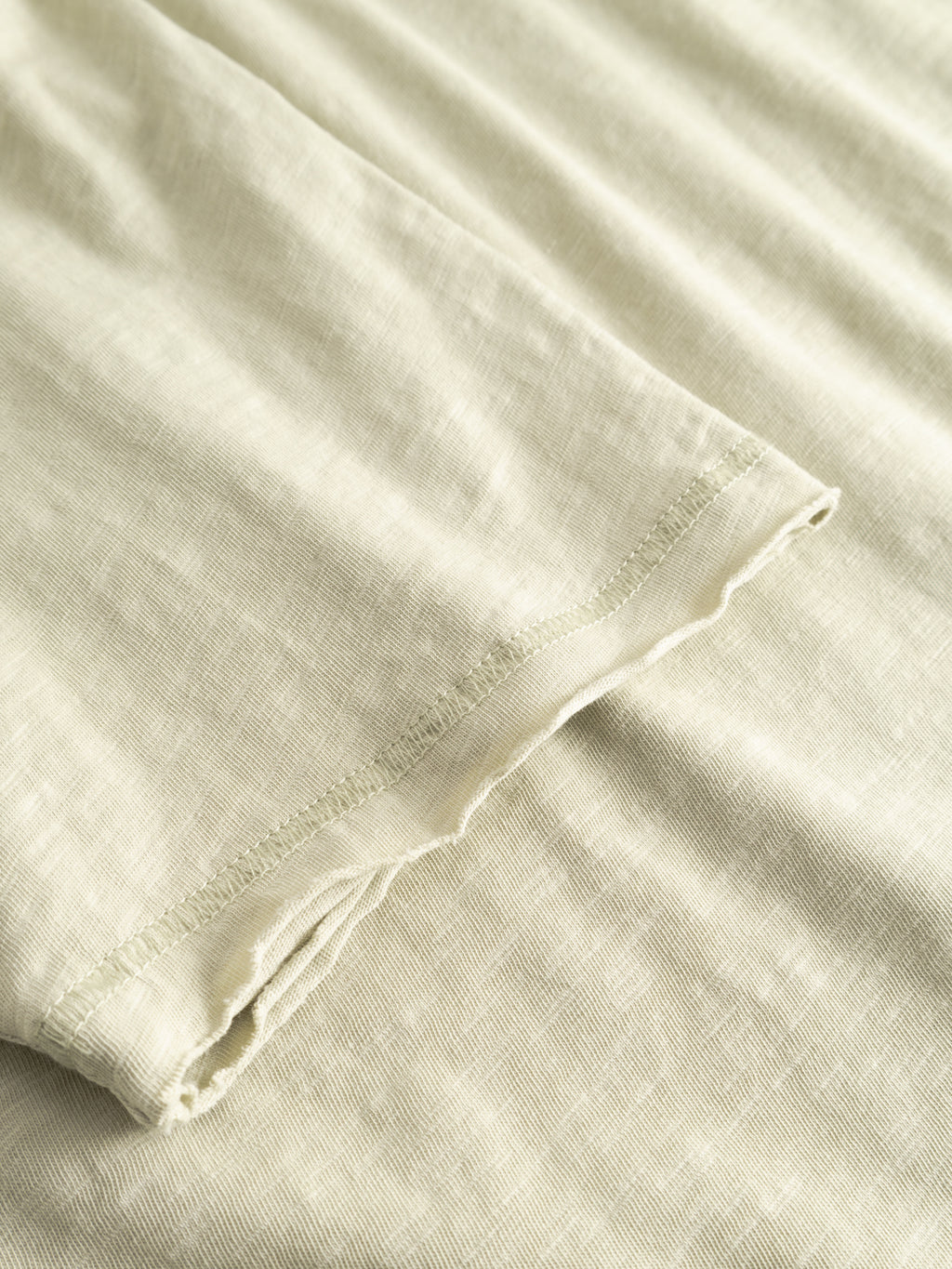 Close-up of the Gabba GABkostant New SS t-shirt in Alfa Green, featuring visible stitching along the edge and showcasing its soft, subtly textured slub fabric laid flat.