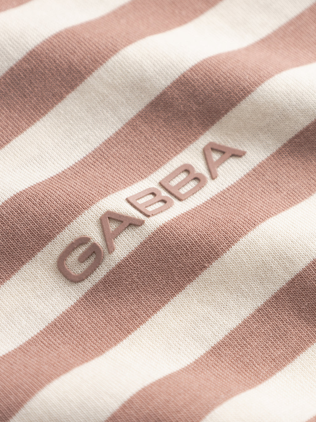 Close-up of Gabba's GABdune Logo Stripes SS GOTS t-shirt in Wood Pink, showing its light pink and off-white striped, GOTS-certified fabric with 
