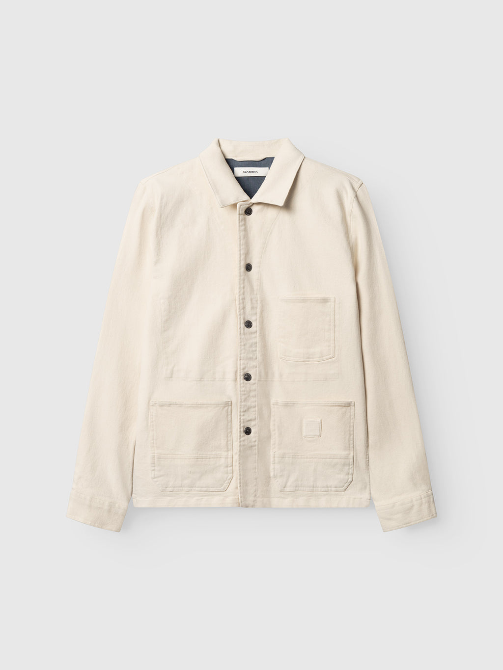 The Gabba GABbeta Twill - Ecru is a cream-colored garment dyed overshirt featuring long sleeves, a collar, front button closure, and three visible front pockets, shown on a light gray background.
