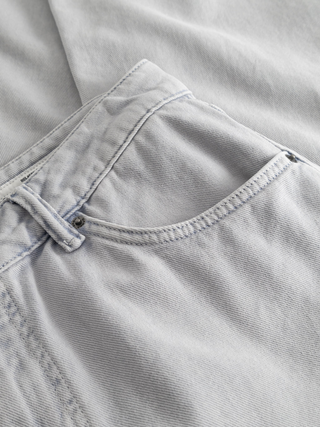 Close-up of GABcarl Antiq Jeans by Gabba in denim blue, showcasing the front pocket, waistband, visible stitching, and rigid twill texture of these relaxed tapered jeans.