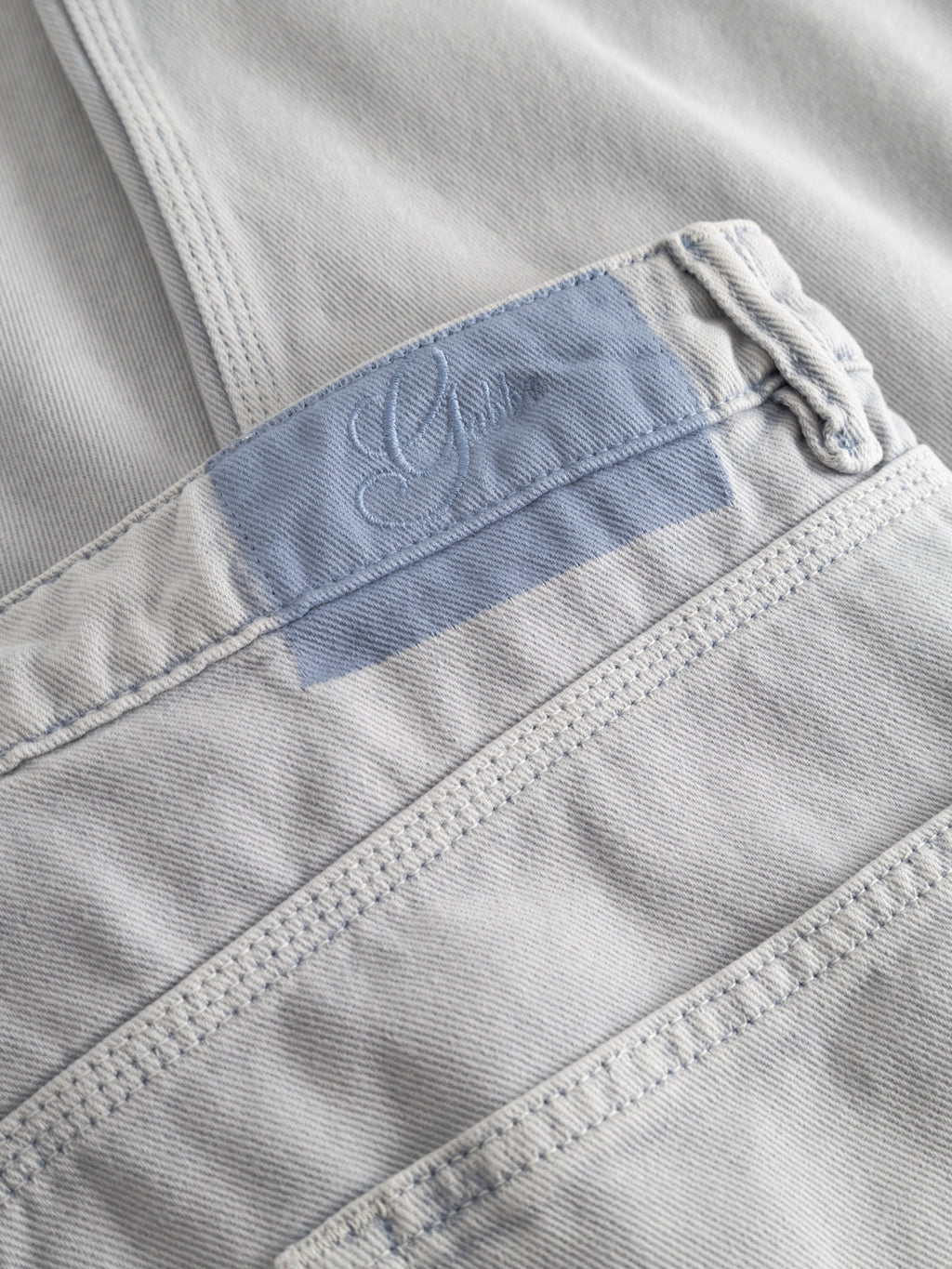 Close-up of Gabba GABcarl Antiq Jeans in denim blue, showcasing the relaxed tapered pocket with a blue patch, embroidered text, and visible stitching on rigid twill fabric.