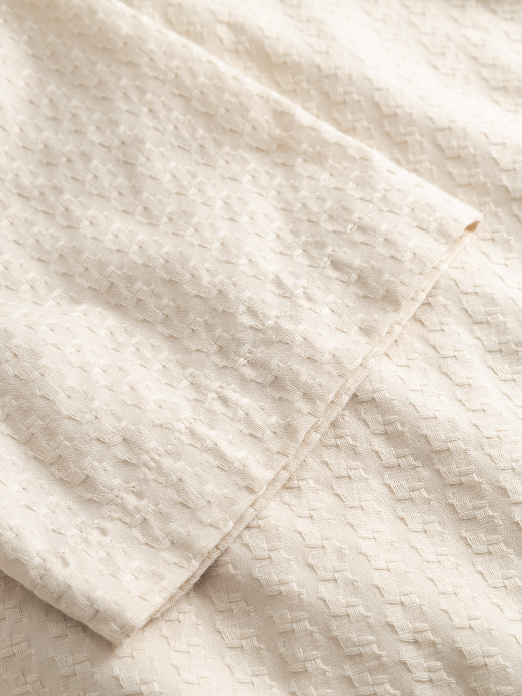 Close-up of the Gabba GABtimo Resort Neal SS Shirt in Birch shows light beige textured fabric with a subtle check pattern, visible seams, and soft folds. Its slightly raised jacquard 3D motif adds visual interest—ideal for resort wear.